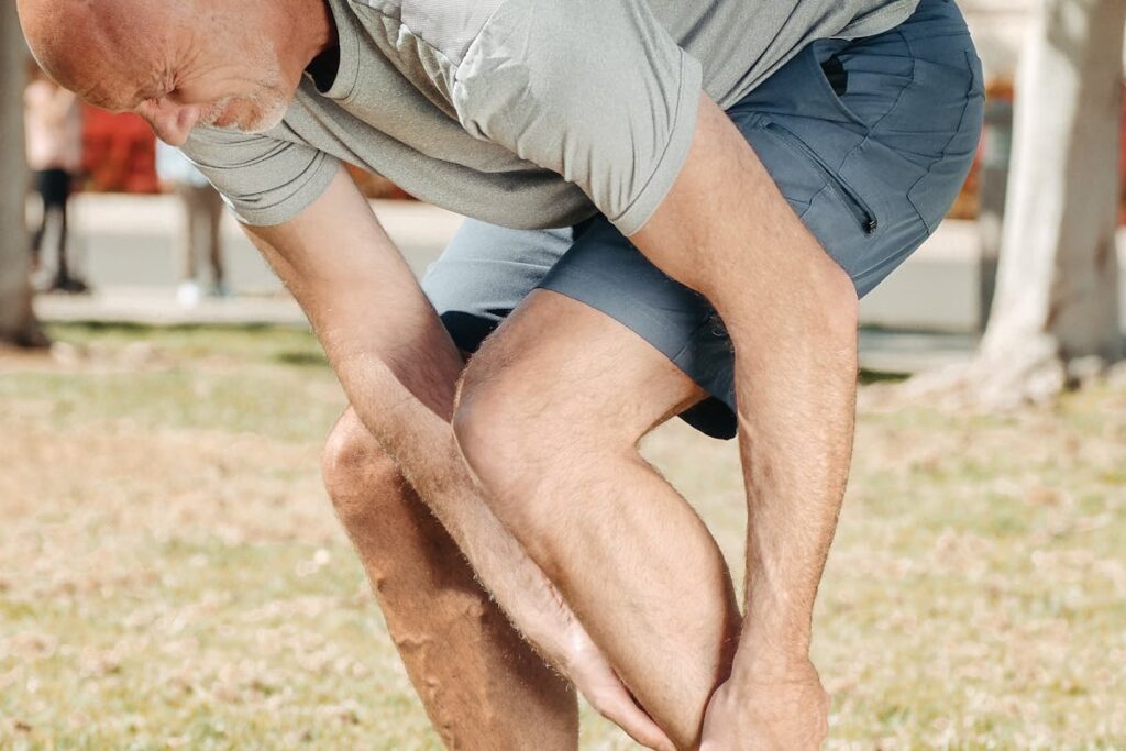 A Bald Man Holding His Injured Ankle