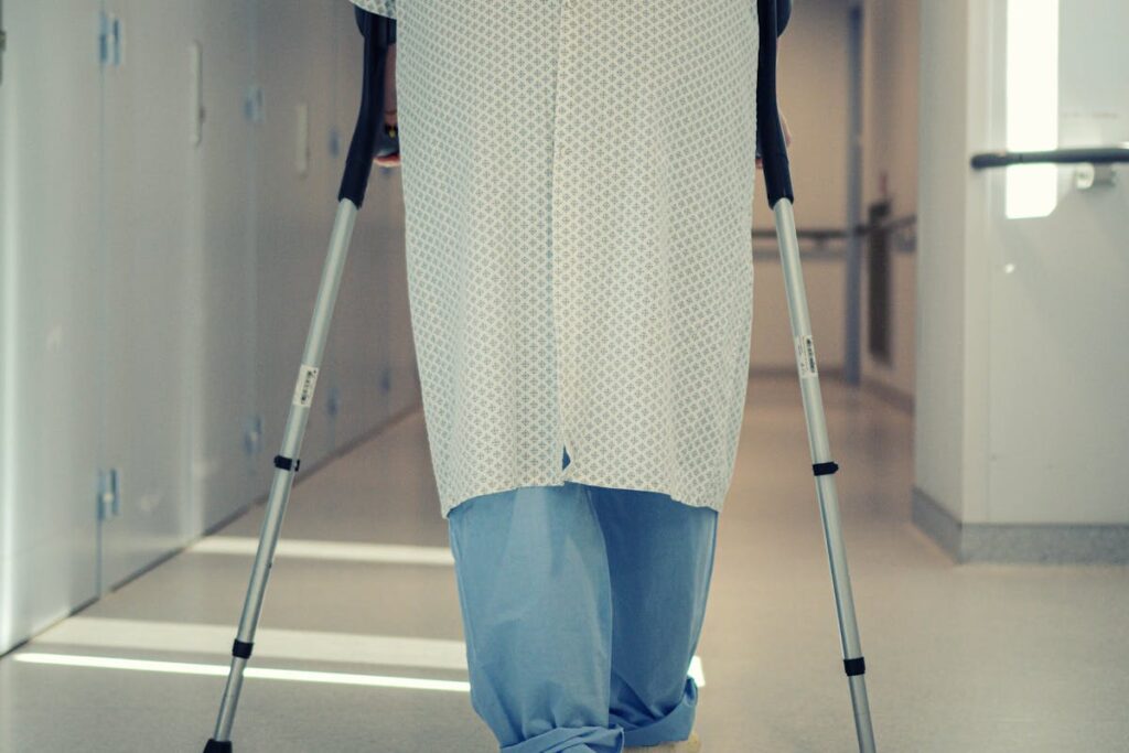 Rear View of a Patient Walking With Crutches on a Hospital Corridor